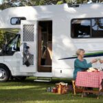 a senior couple sit at a picnic table in front of their RV