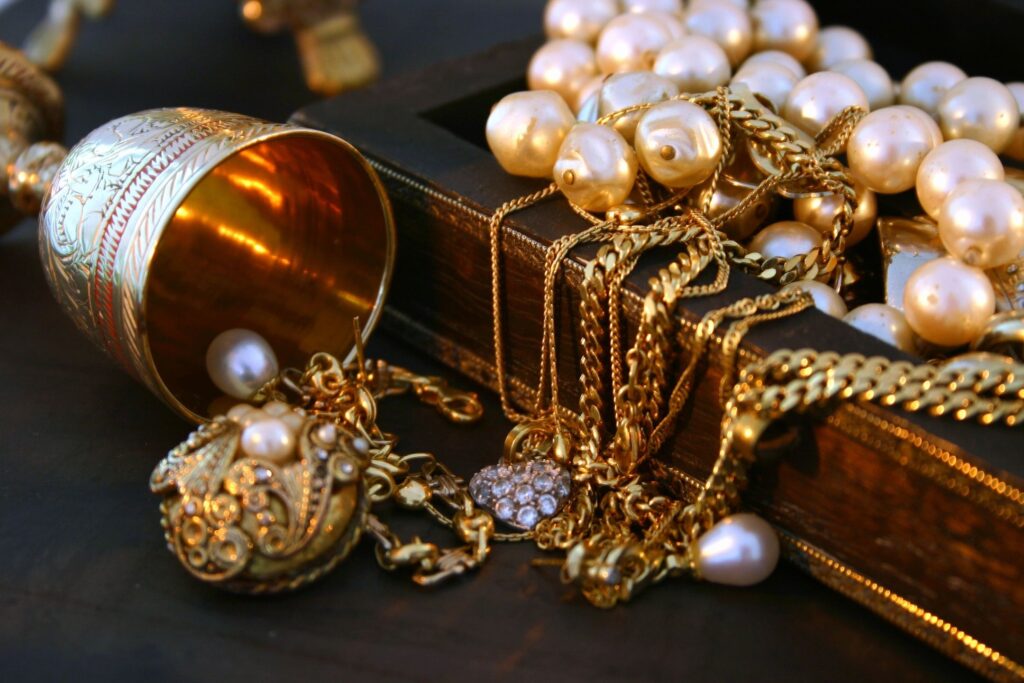 gold chains, pearls, and other jewelry draped over a jewelry box