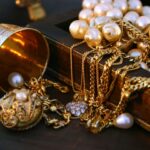 gold chains, pearls, and other jewelry draped over a jewelry box